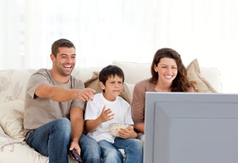 Family laughing while watching television together in the living-room