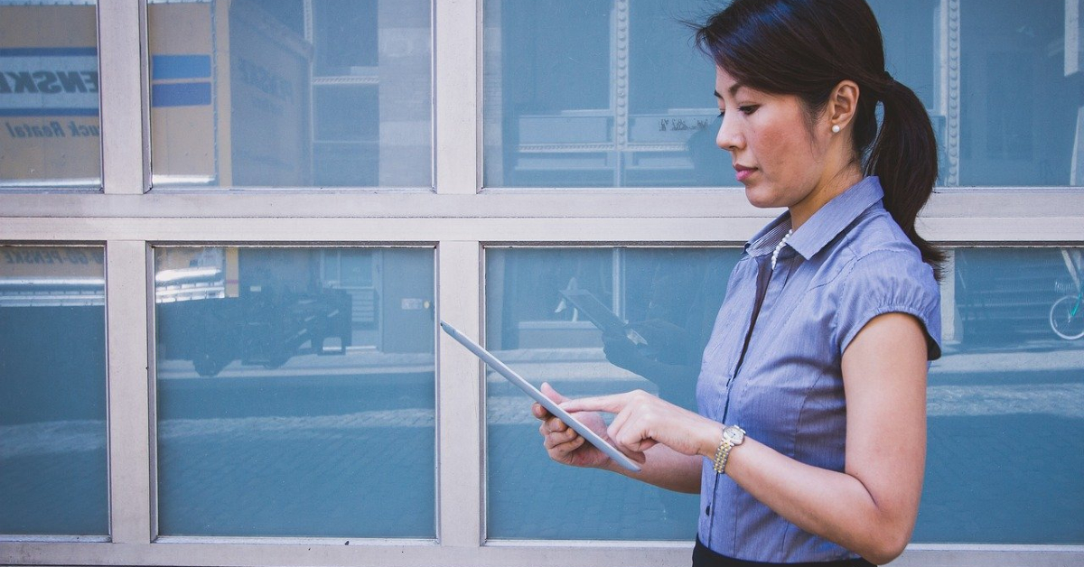 Woman on tablet infront of windows on a building